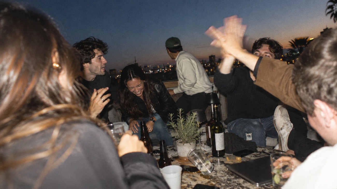 Friends on a rooftop at dusk, mid celebration